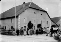 Personnes avec des boeufs devant une maison
