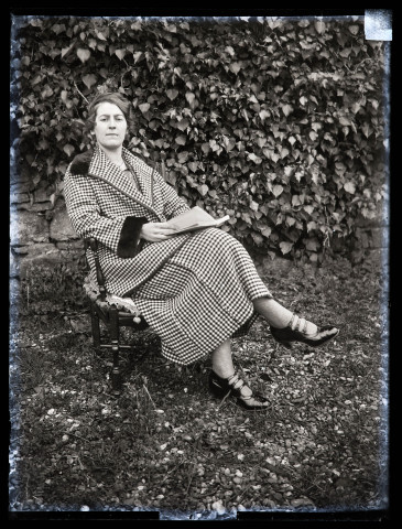 Portrait d'une jeune femme assise en extérieur, avec un livre.