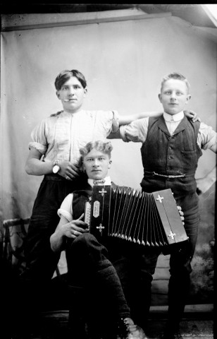 Trois hommes dont un jouant de l'accordéon