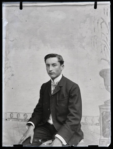 Portrait de Jean Rameaux assis devant un décor peint.