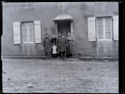 Famille avec trois militaires canadiens devant une habitation.