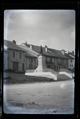 Monument aux morts, une rangée d'habitations mitoyennes en arrière-plan.