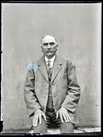 Portrait d'un homme assis portant un costume clair.