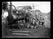 Hommes autour d'une "locomobile", machine à vapeur permettant de faire fonctionner une batteuse ; le cousin (de Desnes) d'Agathe Coutemoine est assis dans l'herbe.