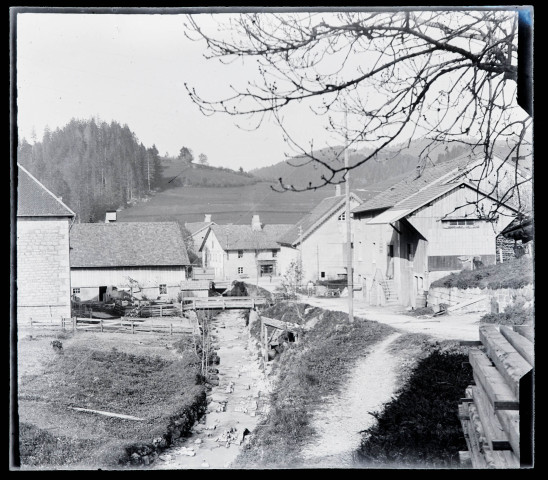 Rue, maisons et cours d'eau à Les Gras.