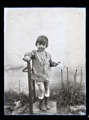 Portrait d'un petit garçon tenant une clé, debout sur un prie-Dieu.