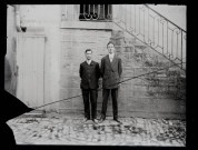 Portrait de Jean Rameaux (à gauche) et du cousin de Desnes devant un bâtiment.