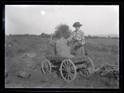 Agathe Coutemoine, à côté de la voiturette à bras chargée de sacs de pommes terres, tient deux énormes tubercules provenant de la récolte effectuée près de Vers-en-Montagne.