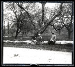 Trois femmes assises sur un tronc, derrière elles un homme est assis dans la fourche d'un arbre. De gauche à droite : Mathilde Coutemoine, Maurice de Pagnoz, Emilie Vuillaume, Agathe Coutemoine (avec un sac devant contenir un appareil photographique).