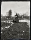 Femme assise devant des pierres blanches avec des petits chiens noirs.
