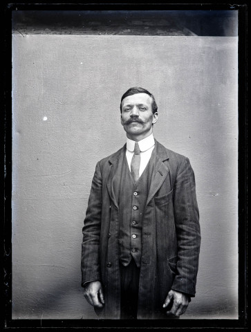 Portrait d'un homme debout portant un costume rayé.
