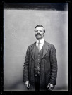 Portrait d'un homme debout portant un costume rayé.