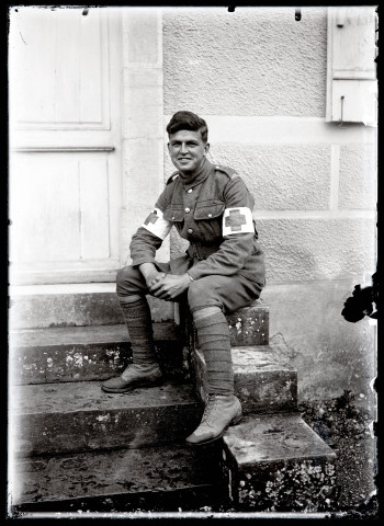 Portraits du Corps des forestiers canadiens et autres troupes : militaire du service médical souriant, assis sur une marche.