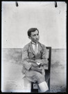 Portrait de Jean Rameaux assis sur une chaise, le journal "Photo-revue" dans les mains.