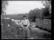 Jeune femme assise sur un rocher au bord de l'eau, la roue à aubes du petit moulin de Vers-en-Montagne en arrière plan.