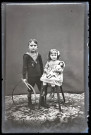 Portrait de deux enfants avec des jouets, la fillette assise tient une poupée dans les bras, le petit garçon debout tient un cerceau.