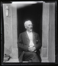 Portrait d'Elisée Coutemoine assis devant une porte ouverte.