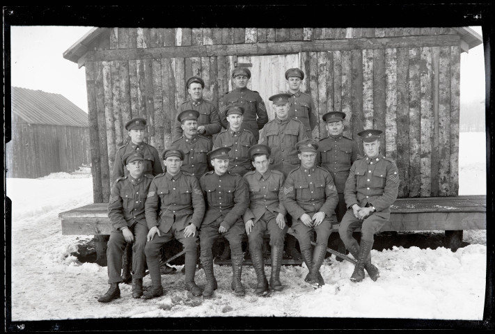 Portraits du Corps des forestiers canadiens et autres troupes : groupe de militaires en uniforme posant dans la neige devant un baraquement en bois.