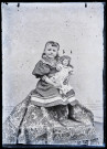 Portrait d'une fillette assise, une poupée dans les bras.