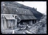 Groupe devant une scierie, un travailleur porte une planche de bois.