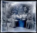 Portrait de groupe, Emilie Vuillaume assise à gauche avec un journal dans les mains, son époux Elisée Coutemoine debout derrière elle.