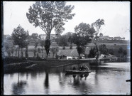 Trois hommes dans une barque, un village en arrière-plan.