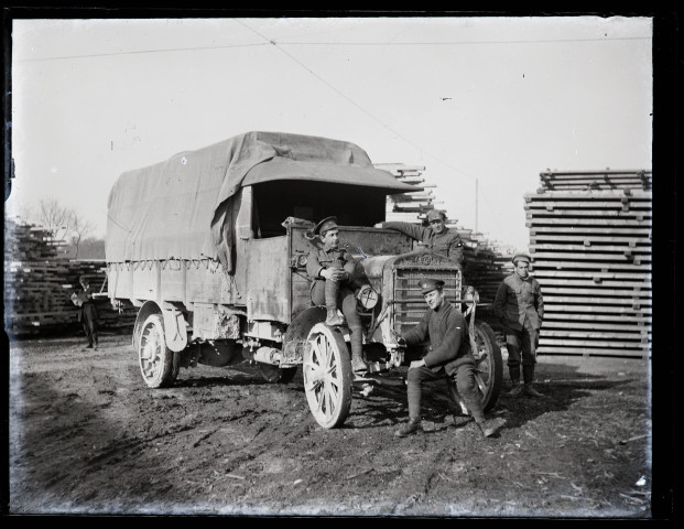 Exploitation de la forêt de la Joux par les soldats canadiens : quatre militaires posant avec un camion, des planches de bois en arrière-plan.