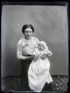 Portrait d'une femme assise tenant un bébé en tenue de baptême.