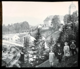 Reproduction d'un cliché de quatre enfants posant devant une voie ferrée et un édifice religieux.