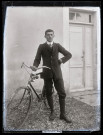 Portrait de jeune homme tenant une bicyclette.