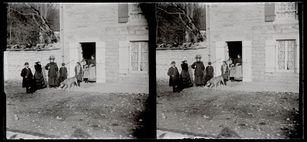 Groupe avec un chien devant une maison.