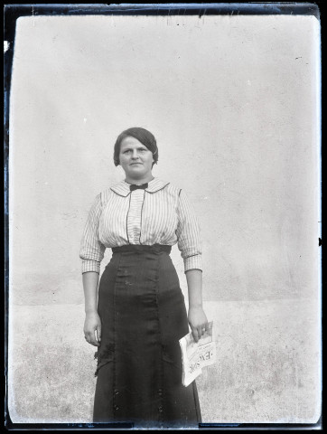 Portrait d'une femme debout tenant un journal dans la main.