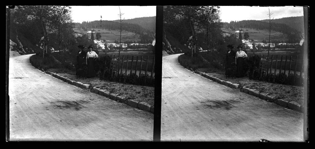 Paysage vallonné, deux femmes et un chien au bord d'une route.