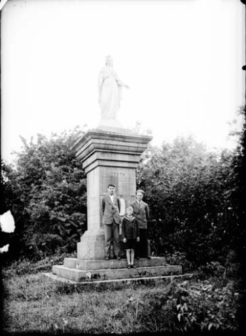 Trois garçons devant une statue