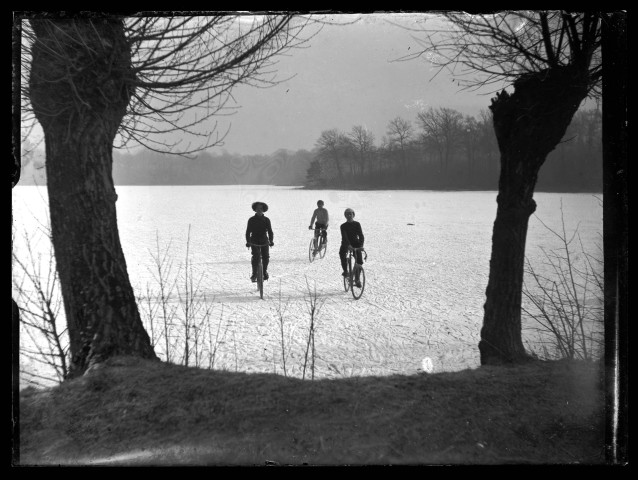 Trois cyclistes traversent l'étang du Pasquier gelé.