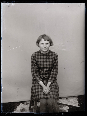 Portrait assis d'une fille portant une robe à carreaux.