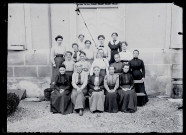 Dix-sept femmes devant les marches du pensionnat de jeunes filles rue du Tatet à Vers-en-Montagne, Agathe Coutemoine assise au premier rang, deuxième place à gauche.