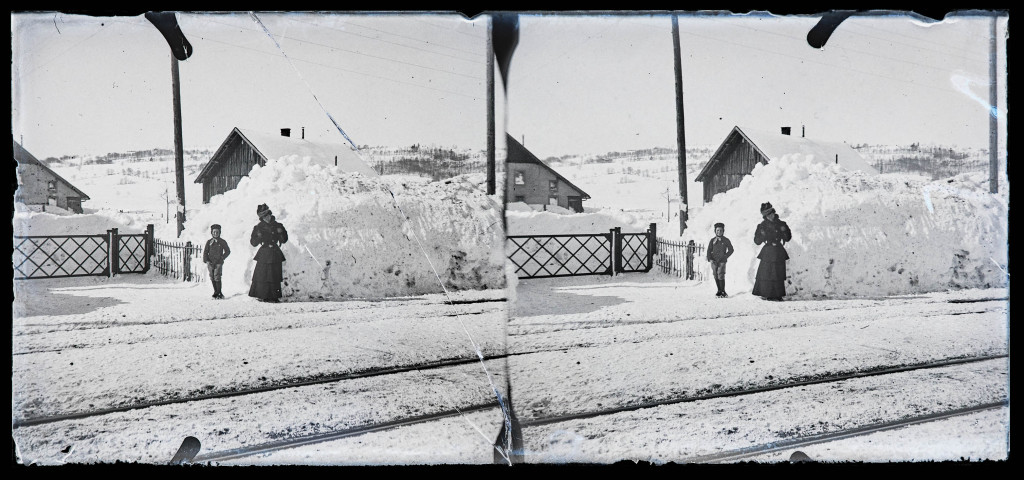 Femme et enfant au pied d'un tas de neige, à côté d'un passage à niveau.