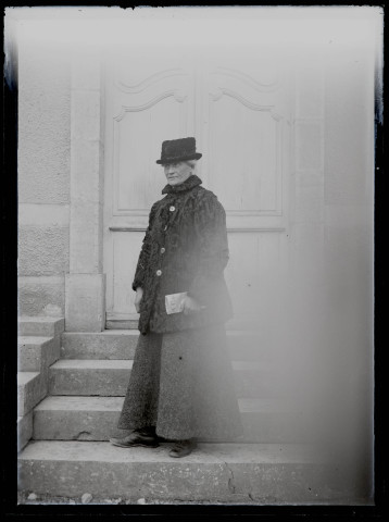 Portrait d'Agathe Coutemoine tenant un journal, sur les marches du pensionnat de jeunes filles rue du Tatet à Vers-en-Montagne.