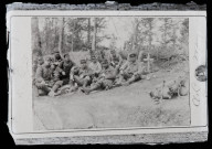 Reproduction d'un cliché d'un groupe de soldats assis à côté d'une tombe.