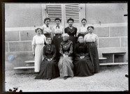 Neuf femmes sur les marches du pensionnat de jeunes filles rue du Tatet à Vers-en-Montagne, Agathe Coutemoine assise au centre du premier rang.